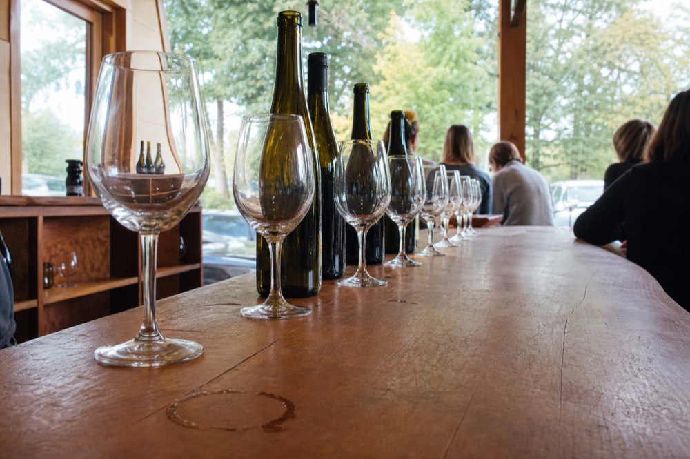 A winery tasting room bar with glasses lined up beside bottles