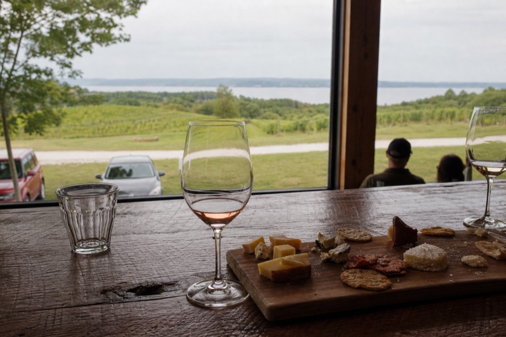 A charcuterie and snack board on a tasting room counter beside wine glasses