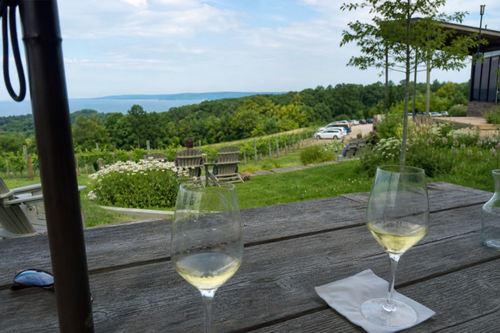 Patio table with wine glasses overlooking a lake between two hills
