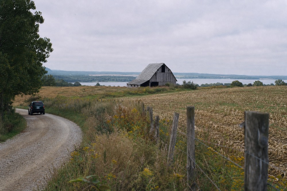 A country road curving through rolling Leelanau farmland with a barn in the distance