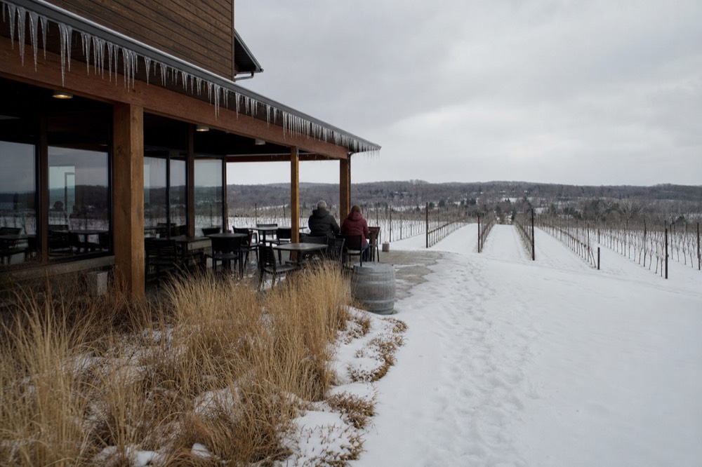 Vineyard rows under fresh snow beside a quiet tasting room building